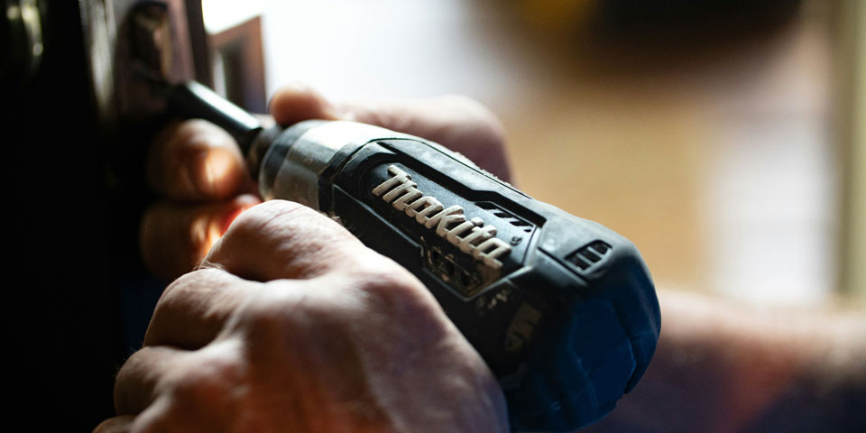 A man working with electric drill installing a door knob